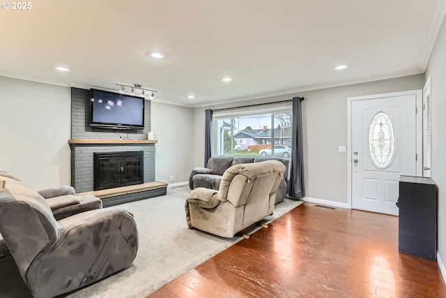 living room with a fireplace, hardwood / wood-style floors, and ornamental molding