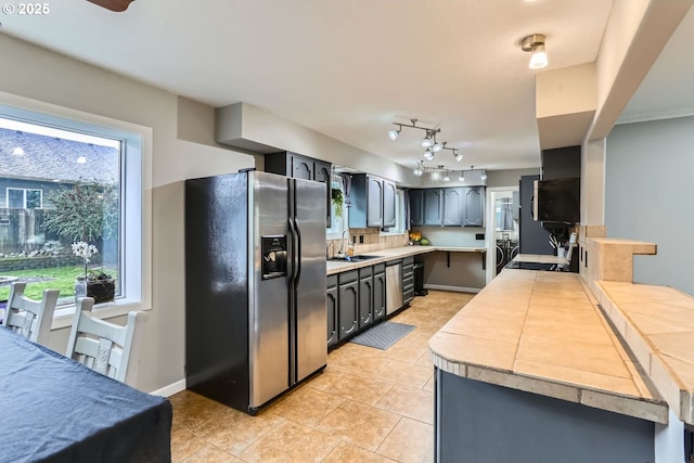 kitchen featuring a healthy amount of sunlight, stainless steel fridge with ice dispenser, sink, and tasteful backsplash