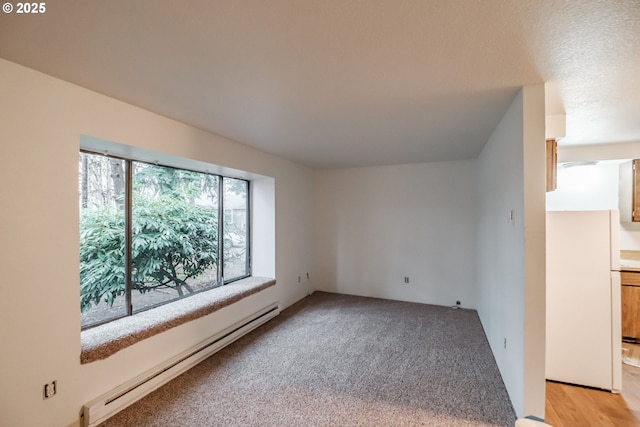 unfurnished room with baseboard heating and light colored carpet