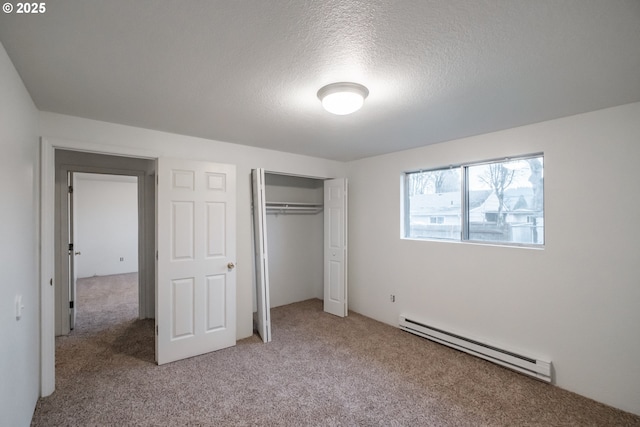 unfurnished bedroom with a textured ceiling, baseboard heating, a closet, and carpet flooring