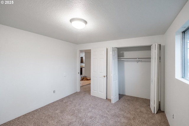 unfurnished bedroom with a closet, light carpet, and a textured ceiling