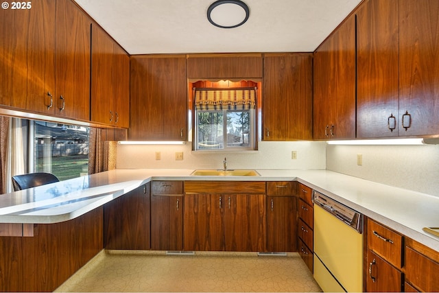 kitchen with dishwasher, sink, a breakfast bar, and kitchen peninsula