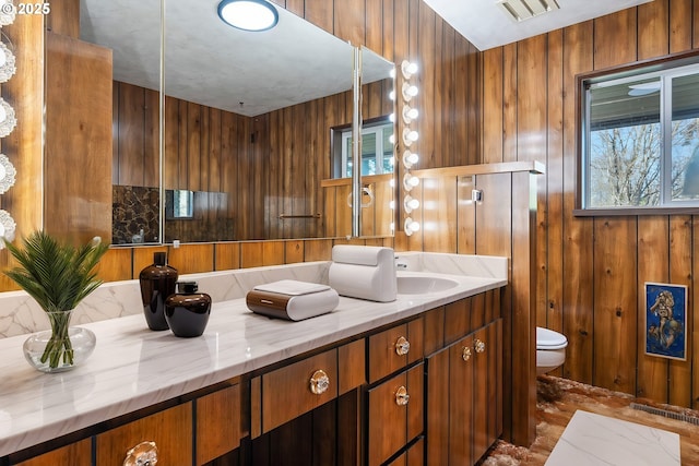 bathroom with vanity, a wealth of natural light, wooden walls, and toilet