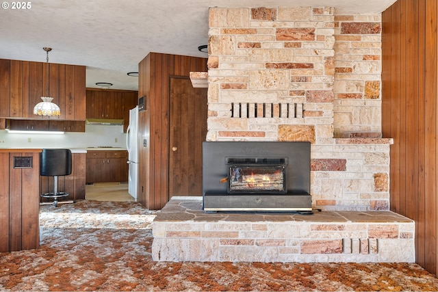 room details with a fireplace, white fridge, a textured ceiling, and wood walls