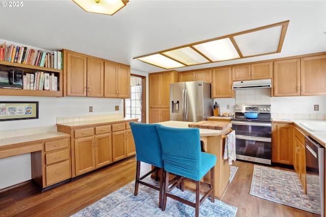 kitchen with tile countertops, appliances with stainless steel finishes, light wood-type flooring, and under cabinet range hood