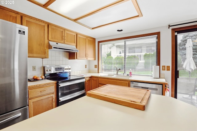 kitchen with under cabinet range hood, appliances with stainless steel finishes, light countertops, and a sink