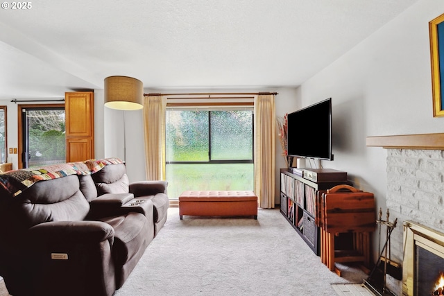 carpeted living area featuring a stone fireplace