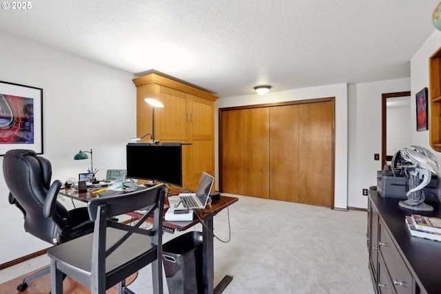 office area featuring light carpet, baseboards, and a textured ceiling