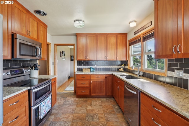 11731 SE 35th Ave, Milwaukie, OR 97222 - kitchen with stainless steel appliances, a sink, decorative backsplash, stone finish flooring, and brown cabinetry