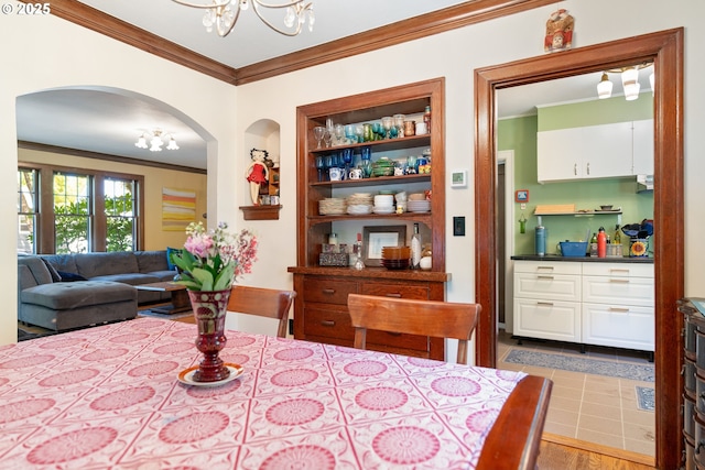 2406 SE 30th Ave, Portland, OR 97214 - dining room with a chandelier, crown molding, arched walkways, built in shelves, and wood finished floors