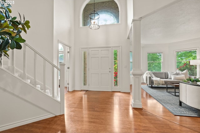 13460 Snowberry Ct, Lake Oswego, OR 97035 - foyer entrance with stairs, hardwood / wood-style flooring, decorative columns, a towering ceiling, and a textured ceiling