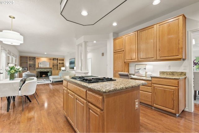 13460 Snowberry Ct, Lake Oswego, OR 97035 - kitchen featuring ornate columns, gas stovetop, a fireplace with raised hearth, a kitchen island, and light wood finished floors