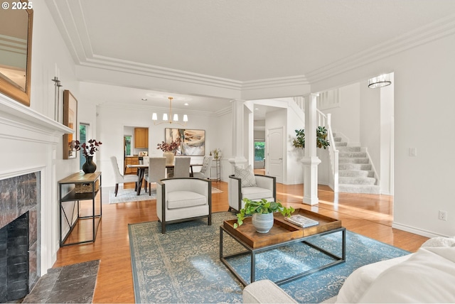 13460 Snowberry Ct, Lake Oswego, OR 97035 - living room with a high end fireplace, ornate columns, light wood-style floors, stairs, and crown molding