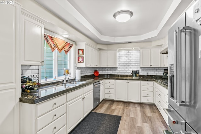 kitchen featuring light wood finished floors, a sink, white cabinetry, stainless steel appliances, and tasteful backsplash