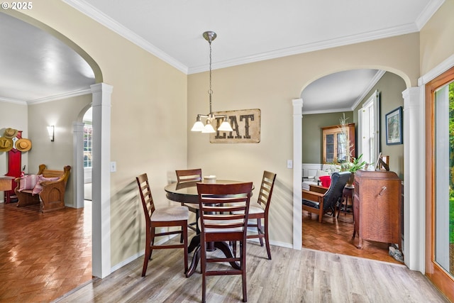dining space with arched walkways, crown molding, ornate columns, and wood finished floors