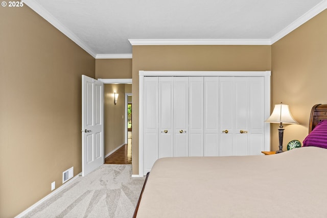carpeted bedroom featuring baseboards, ornamental molding, a closet, and visible vents