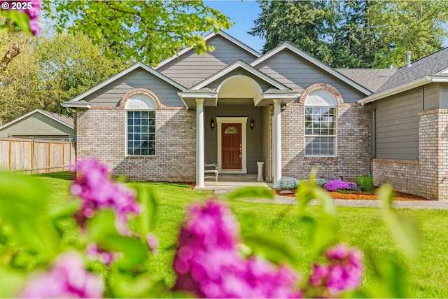 view of front facade with brick siding, fence, and a front yard