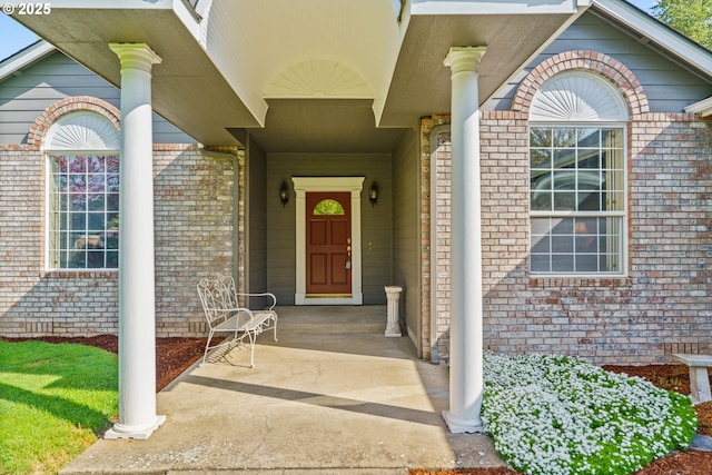 view of exterior entry with covered porch and brick siding