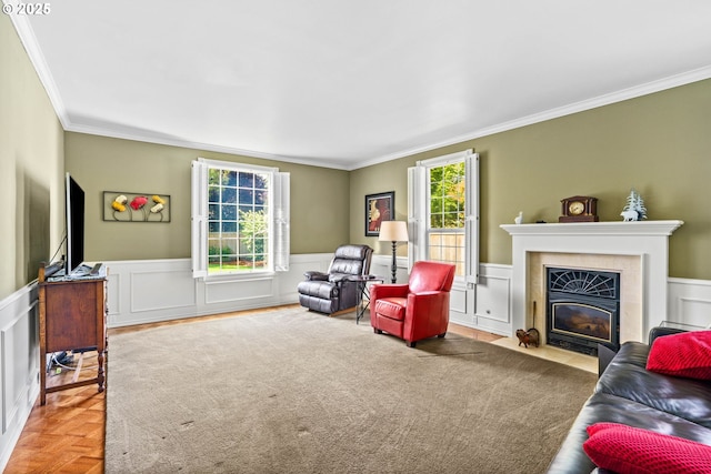 sitting room with ornamental molding, a high end fireplace, a decorative wall, and a wainscoted wall