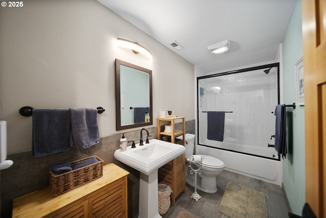 full bathroom featuring tile walls, visible vents, bath / shower combo with glass door, and toilet