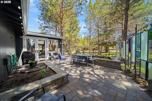 view of patio featuring grilling area, outdoor dining area, french doors, and fence