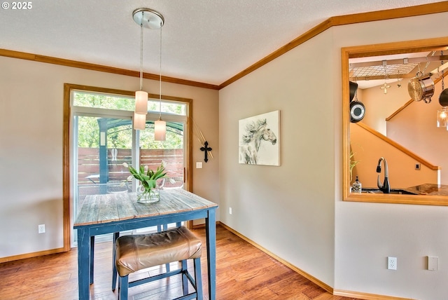 dining room with crown molding, light wood finished floors, and baseboards