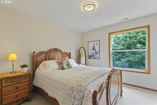 bedroom featuring light colored carpet, baseboards, and a textured ceiling