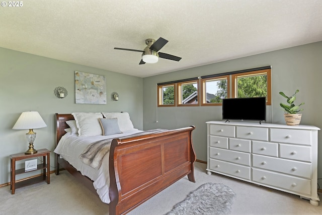 bedroom featuring light carpet, a ceiling fan, and a textured ceiling