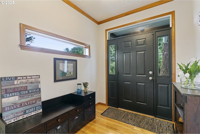 foyer featuring light wood-style flooring, ornamental molding, and baseboards