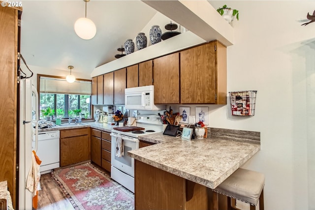 15940 SW 88th Ave, Tigard, OR 97224 - kitchen featuring white appliances, a peninsula, brown cabinetry, a breakfast bar, and light wood finished floors