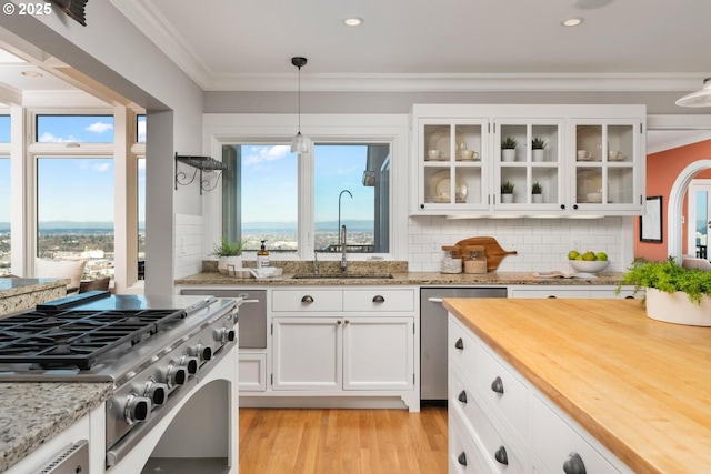 kitchen with decorative backsplash, appliances with stainless steel finishes, sink, decorative light fixtures, and white cabinetry