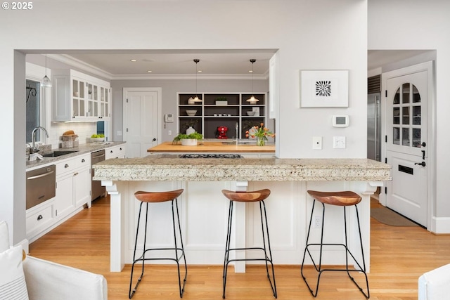 kitchen with a breakfast bar, stainless steel appliances, sink, a center island, and white cabinetry