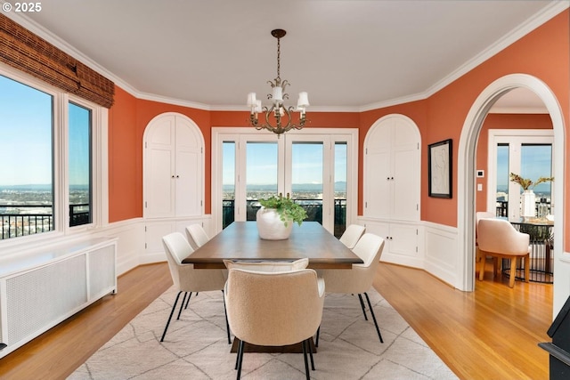 dining room featuring a chandelier, radiator heating unit, ornamental molding, and light hardwood / wood-style flooring