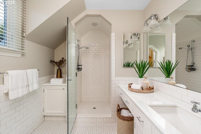 bathroom with tile patterned floors, a tile shower, vanity, and tile walls