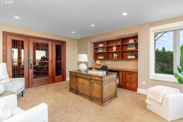 home office featuring built in desk and light carpet