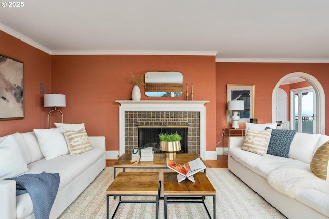 living room featuring light wood-type flooring, crown molding, and a tile fireplace