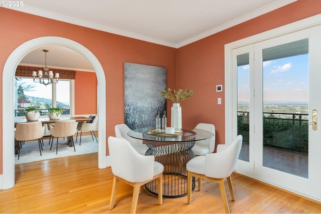 dining space featuring hardwood / wood-style floors, crown molding, and a chandelier