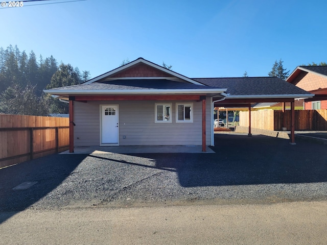 view of front facade featuring a shingled roof and fence