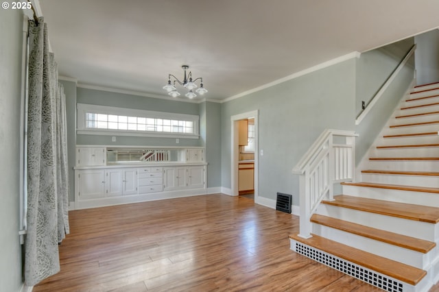 interior space with crown molding, an inviting chandelier, wood finished floors, stairs, and baseboards