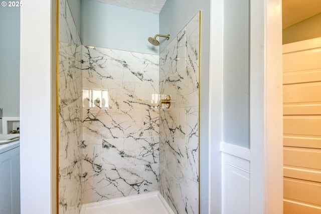 bathroom with washer / clothes dryer and a marble finish shower