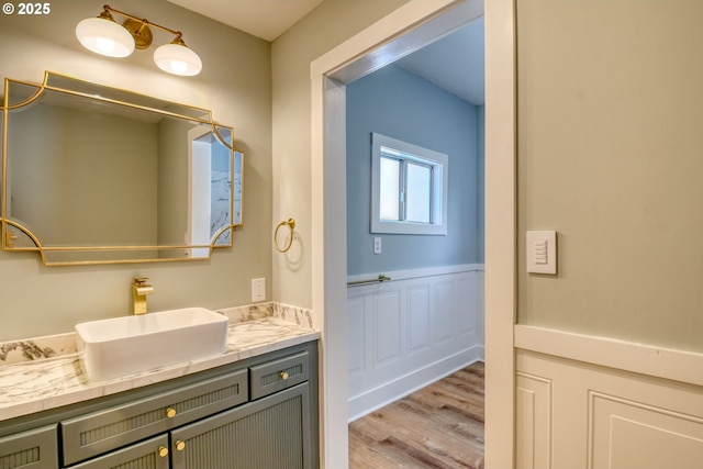 bathroom featuring wood finished floors, vanity, and a wainscoted wall