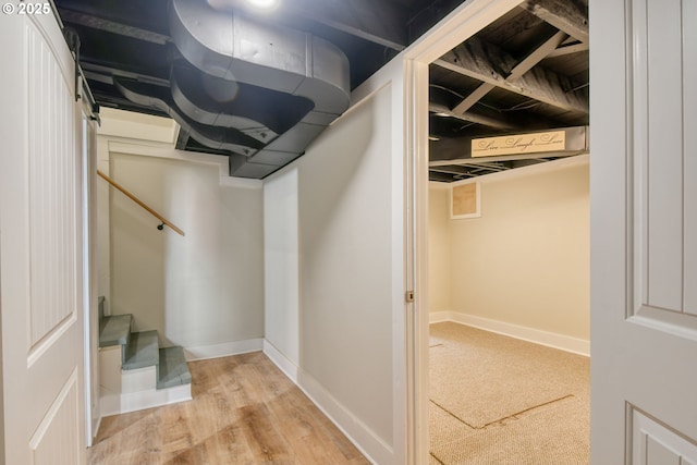 finished below grade area featuring stairway, light wood-style floors, and baseboards