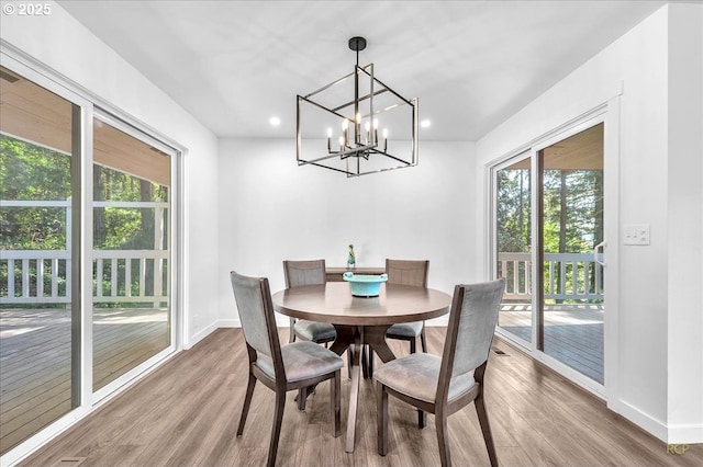 dining space featuring light wood-style floors, baseboards, an inviting chandelier, and recessed lighting