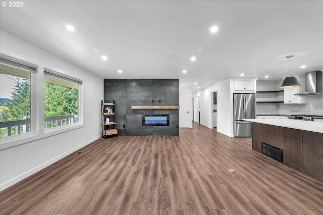 unfurnished living room featuring baseboards, recessed lighting, wood finished floors, and a tile fireplace