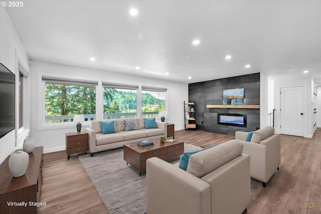 living room with recessed lighting, light wood-style floors, baseboards, and a fireplace
