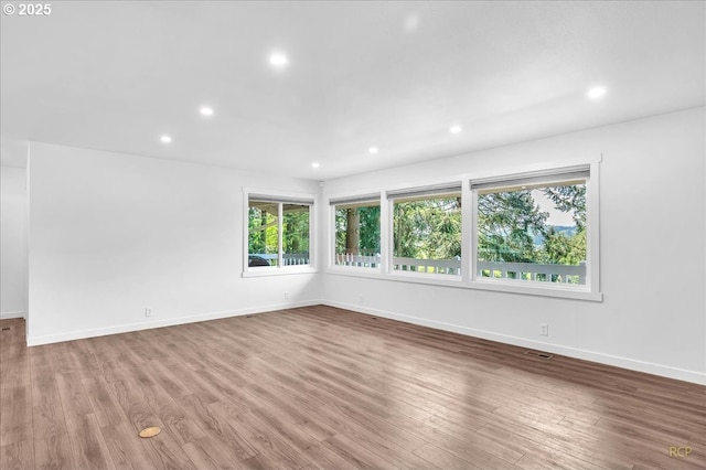 spare room featuring baseboards, recessed lighting, and wood finished floors