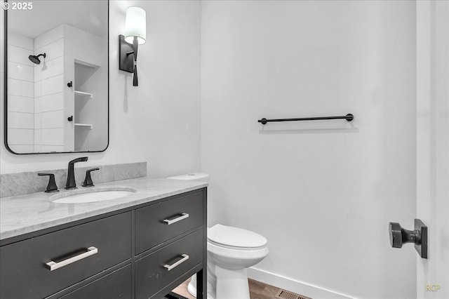 bathroom with toilet, baseboards, wood finished floors, and vanity