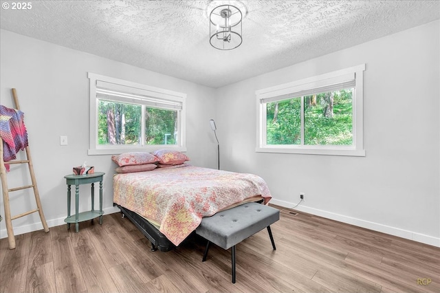 bedroom featuring baseboards, a textured ceiling, and wood finished floors