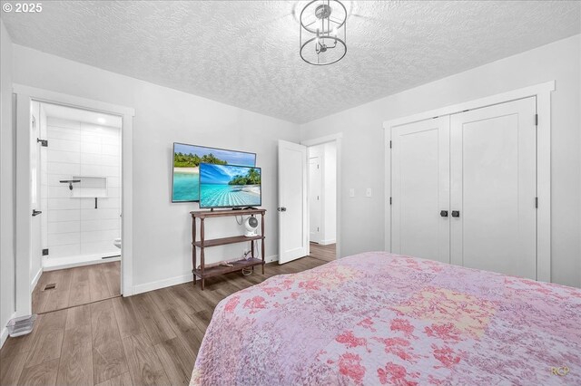 bedroom with a textured ceiling, wood finished floors, baseboards, a closet, and ensuite bathroom