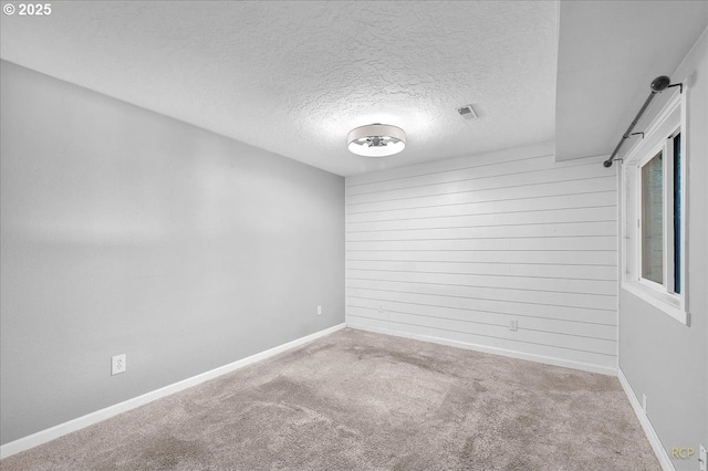 spare room with baseboards, a textured ceiling, carpet, and visible vents